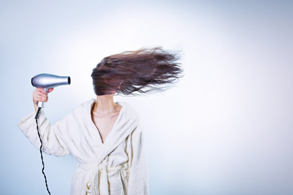 woman blowdrying her hair, showing the hair quality